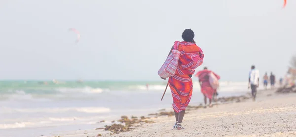 Rear view of traditonaly dressed maasai man selling hand made jewelry on picture perfect tropical Paje beach, Zanzibar, Tanzania, East Africa. — Stock Photo, Image