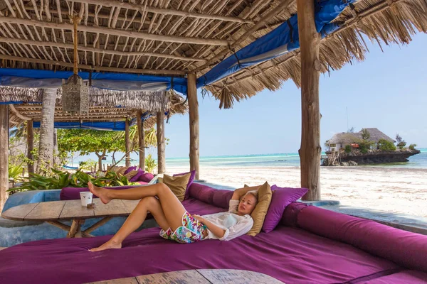 Relaxed woman in luxury tropical bar lounger, enjoying summer vacations on beautiful beach.