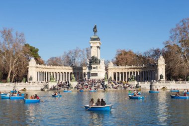Madrid, İspanya - 24 Ocak 2016: geleneksel mavi tekneler Retiro Şehir Parkı gölde üzerinde Ocak 24 bir güzel güneşli kış gününde Madrid, İspanya'kürek turist.