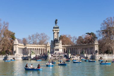 Geleneksel kürek turist Retiro Şehir Parkı gölde gemilerde bir güzel güneşli kış gününde Madrid, İspanya'da mavi.