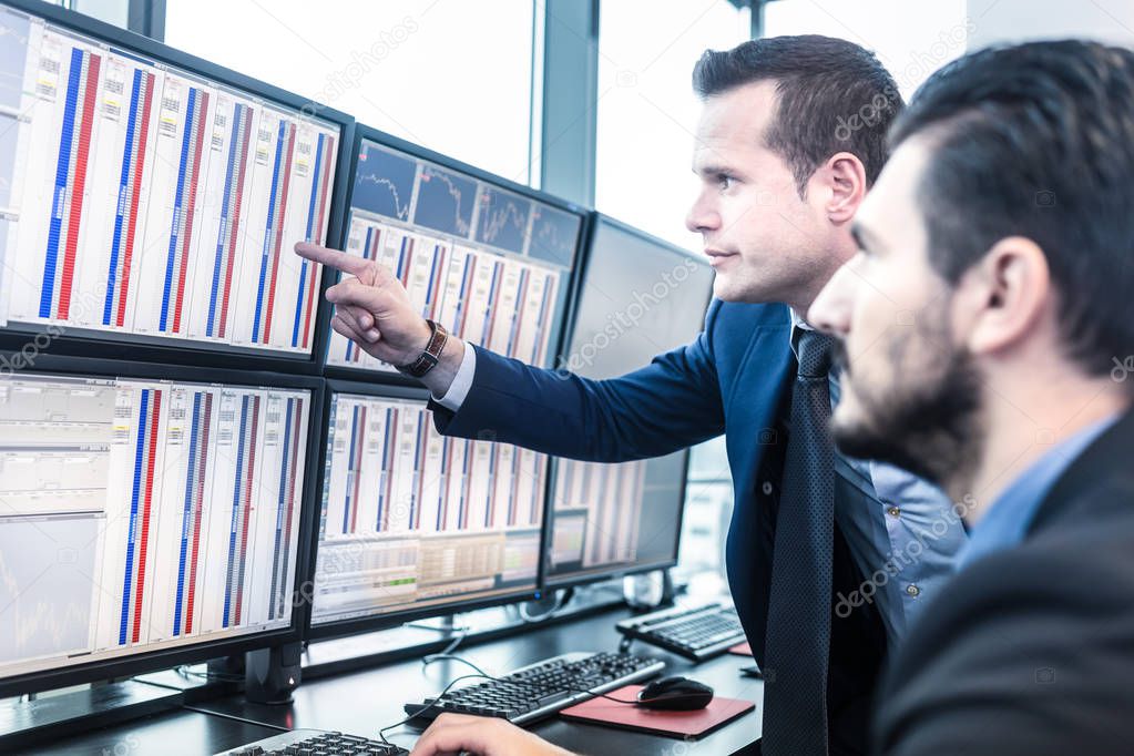 Stock traders looking at market data on computer screens.