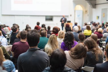 Üniversitedeki konferans salonunda sunum yapan adam.