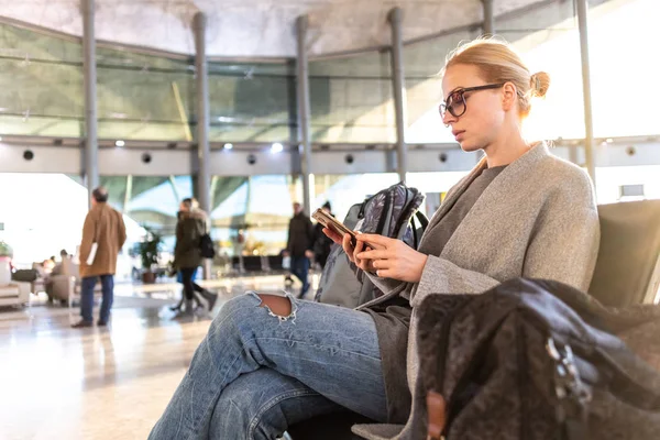 Kvinnliga resenären använder sin mobiltelefon i väntan att gå ombord ett plan på avgångsportarna på flygplatsterminalen. — Stockfoto