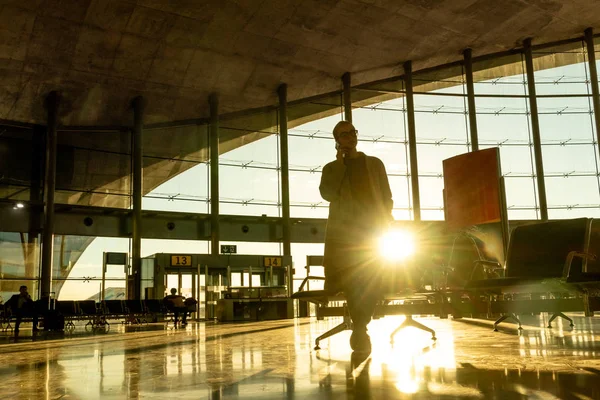 Mulher viajante conversando em seu telefone celular enquanto espera para embarcar em um avião nos portões de partida no terminal do aeroporto . — Fotografia de Stock