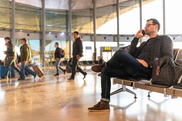 Мужчина-путешественник разговаривает по мобильному телефону, ожидая посадки в самолет на выходе из терминала аэропорта . — стоковое фото