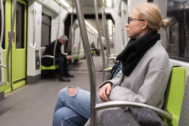 Kış paltonu ve kaşkolünü metroyla seyahat giyen güzel sarışın kadın. Toplu taşıma.