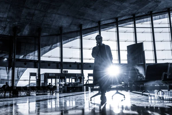 Mulher viajante conversando em seu telefone celular enquanto espera para embarcar em um avião nos portões de partida no terminal do aeroporto . — Fotografia de Stock