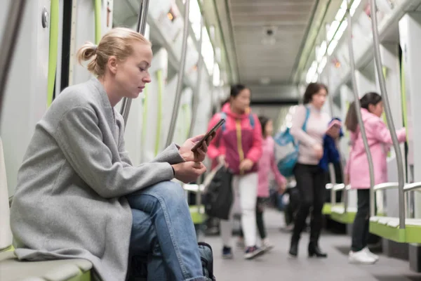 Красива блондинка використовує смартфон під час подорожі на метро громадського транспорту . — стокове фото