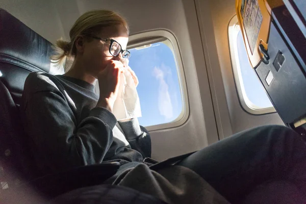 Blonde caucasian woman sneezing while traveling by airplane. — Stock Photo, Image