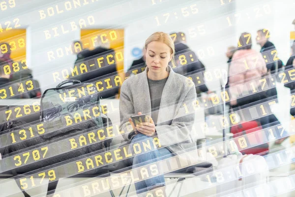 Viajante feminina usando seu telefone celular enquanto espera para embarcar em um avião nos portões de partida no terminal do aeroporto . — Fotografia de Stock