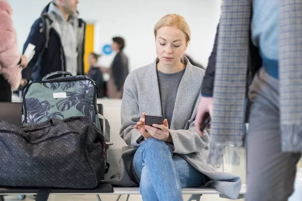 Viaggiatore femminile che usa il suo cellulare in attesa di salire a bordo di un aereo ai gate di partenza al terminal dell'aeroporto . — Foto Stock