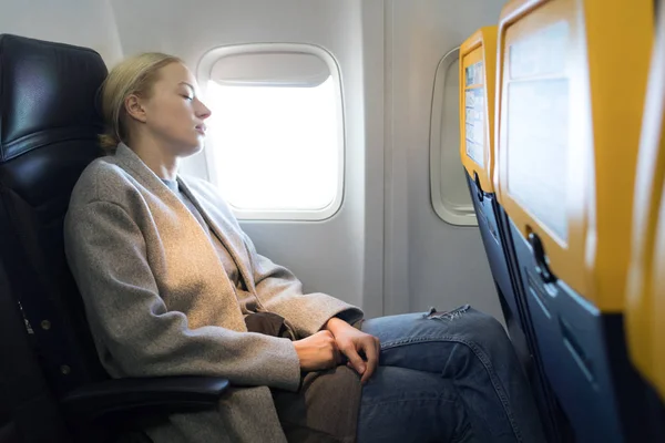 Женщина дремлет на сиденье во время путешествия на самолете . — стоковое фото