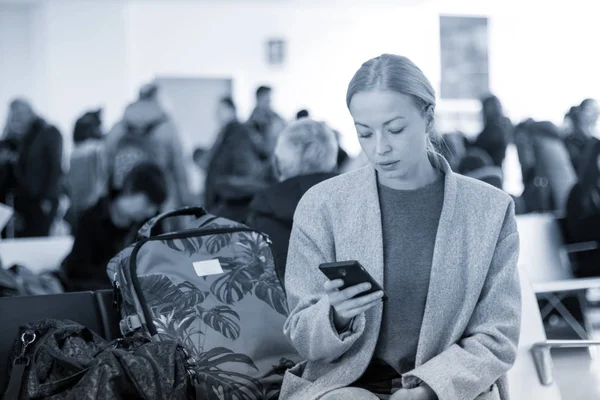 공항 터미널에서 출발 게이트에서 비행기 탑승을 기다리는 동안 그녀의 휴대 전화에 읽고 여성 여행자. — 스톡 사진
