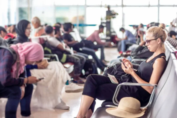 Reisende benutzt ihr Handy, während sie am Abflugsteig des asiatischen Flughafenterminals auf ein Flugzeug wartet. — Stockfoto