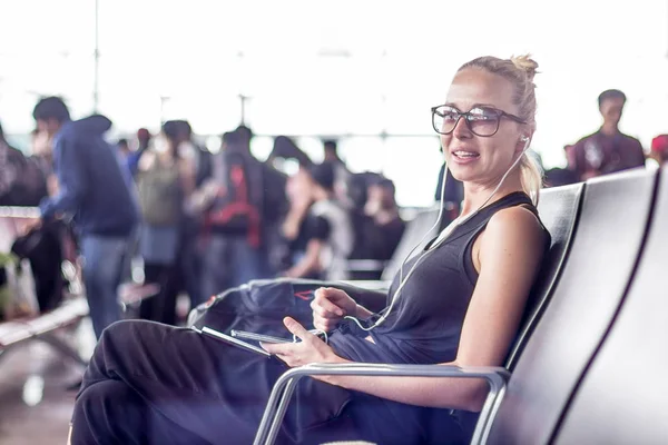 Női utazó használja a mobilját, miközben arra vár, hogy felszálljon egy repülőre az ázsiai repülőtér terminál indulási kapujánál.. — Stock Fotó