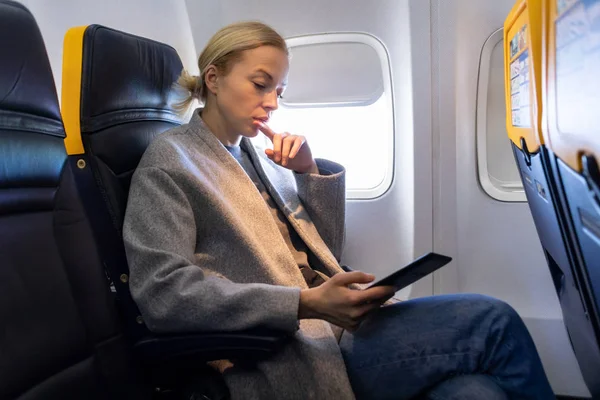 Femme lisant sur e-reader numérique tout en voyageant en avion . — Photo