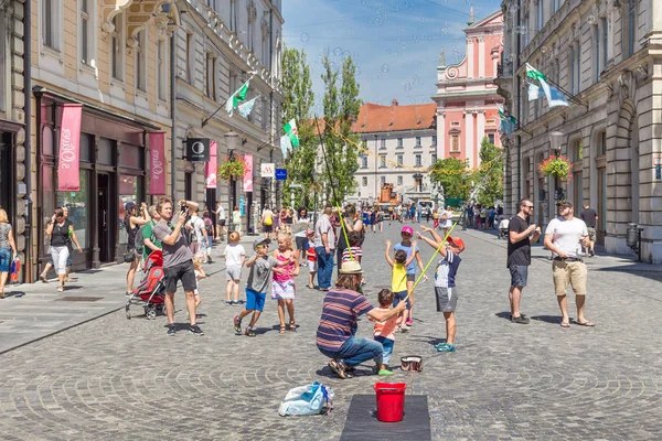 Artista urbano callejero realizando un espectáculo de jabón para niños en el centro medieval de la capital eslovena Liubliana — Foto de Stock