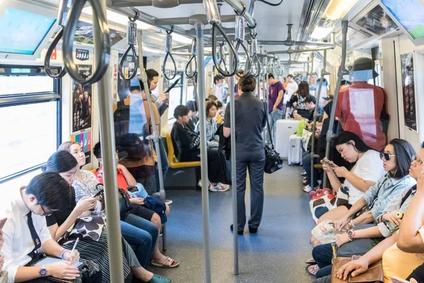 Pasajeros que utilizan sus dispositivos de telefonía móvil mientras viajan en metro de la ciudad en Bangkok, Tailandia — Foto de Stock