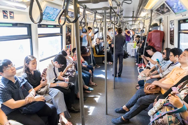 Penumpang menggunakan perangkat telepon genggamnya saat bepergian menggunakan metro kota di Bangkok, Thailand — Stok Foto