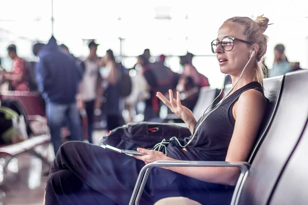 Kvinnlig resenär talar på mobiltelefon medan du väntar på att gå ombord på ett plan vid avgång grindar på asiatiska flygplats terminal. — Stockfoto