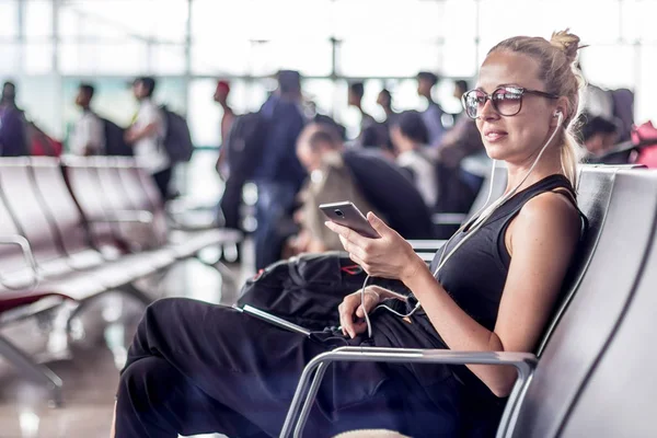 Kvinnlig resenär talar på mobiltelefon medan du väntar på att gå ombord på ett plan vid avgång grindar på asiatiska flygplats terminal. — Stockfoto