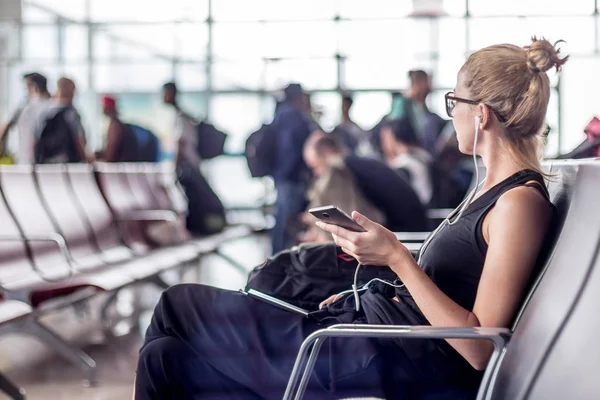 Kadın yolcu, Asya havaalanı terminalinin kalkış kapısında uçağa binmek için beklerken cep telefonuyla konuşuyor.. — Stok fotoğraf