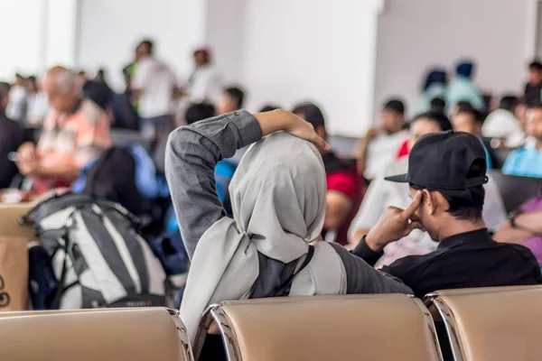 Сучасна мусульманська азіатська пара сидить і чекає вильоту на міжнародний термінал аеропорту — стокове фото