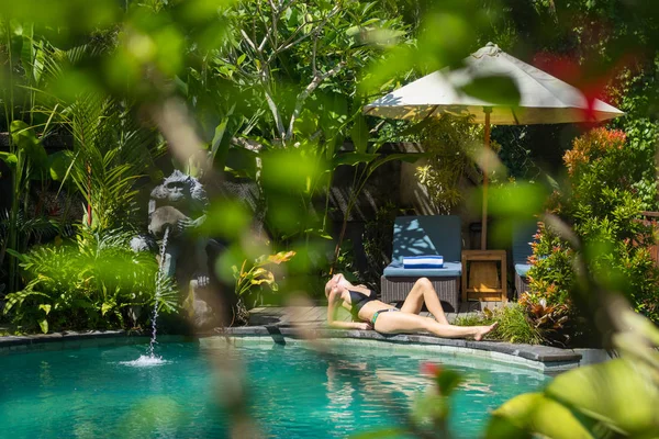 Sensual young woman relaxing in outdoor spa infinity swimming pool surrounded with lush tropical greenery of Ubud, Bali. Royalty Free Stock Images