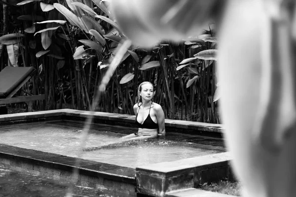 Sensual joven mujer relajante en el spa al aire libre piscina infinita rodeada de exuberante vegetación tropical de Ubud, Bali. Imagen en blanco y negro . —  Fotos de Stock