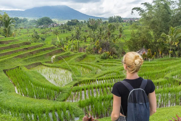Кавказская туристка в маленьком рюкзаке, смотрящая на красивые зеленые рисовые поля и террасы Джатилуви на острове Бали — стоковое фото
