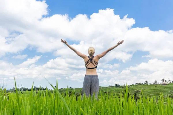 Расслабленная спортивная женщина, руки подняты в небо, наслаждаясь чистой природой на красивых зеленых рисовых полях на Бали . — стоковое фото