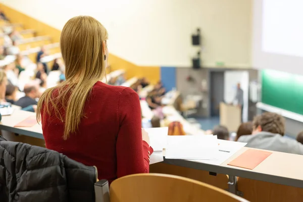 Közönség az előadóteremben. Női diák jegyzetel. — Stock Fotó