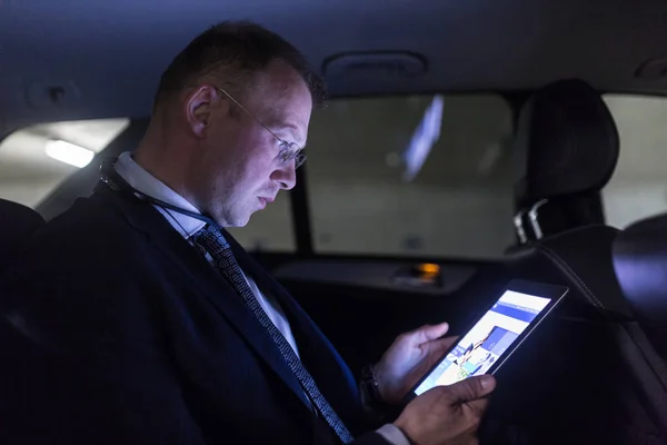 Biznesmen z cyfrowego tabletu, siedzący na tylnym siedzeniu samochodu — Zdjęcie stockowe