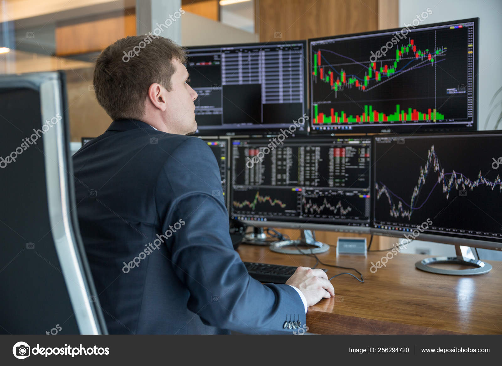 Stock Trader Looking At Computer Screens In Trdading Office
