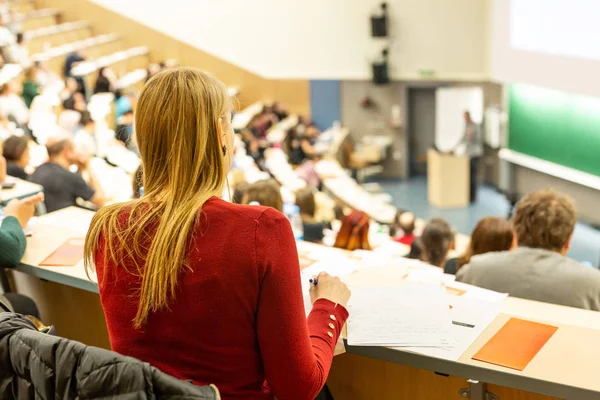 Female student attending faculty lecture workshop making notes. Royalty Free Stock Images