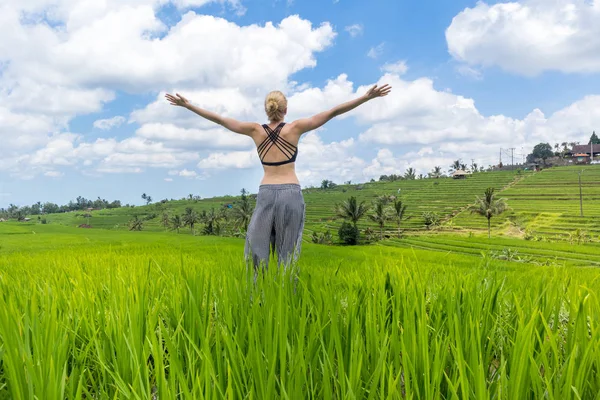 Entspannte, gesunde, sportliche Frau, Arme in den Himmel gereckt, Natur pur auf schönen grünen Reisfeldern auf Bali genießend. — Stockfoto