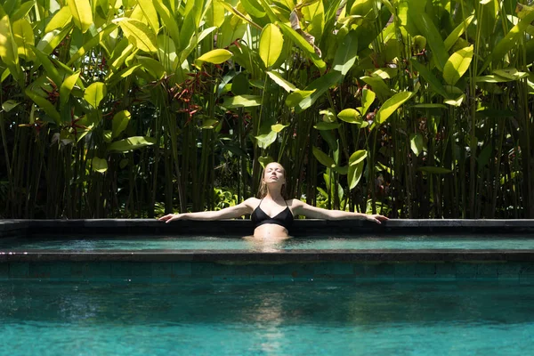 Sensuelle jeune femme relaxante dans un spa extérieur piscine à débordement entourée de verdure tropicale luxuriante d'Ubud, Bali. — Photo