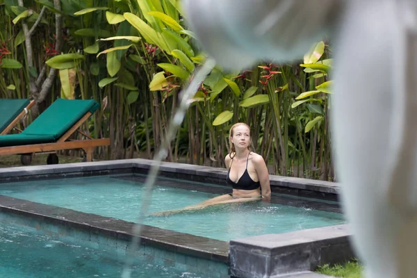 Dışardaki kaplıcada dinlenen şehvetli genç bir kadın sonsuz yüzme havuzunda çevresi yemyeşil Ubud, Bali ile çevrili.. — Stok fotoğraf