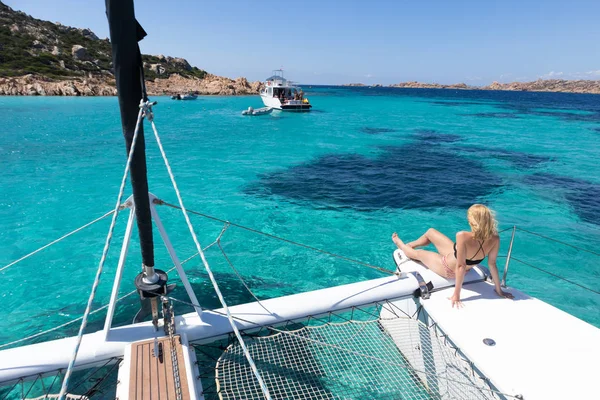 Mujer relajándose en un crucero de vela de verano, sentado en un catamarán de lujo cerca de la imagen perfecta playa de arena blanca en la isla de Spargi en el archipiélago de Maddalena, Cerdeña, Italia. — Foto de Stock