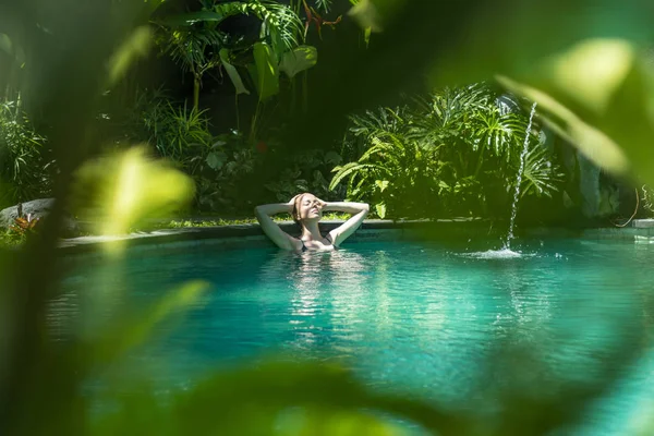 Dışardaki kaplıcada dinlenen şehvetli genç bir kadın sonsuz yüzme havuzunda çevresi yemyeşil Ubud, Bali ile çevrili.. — Stok fotoğraf