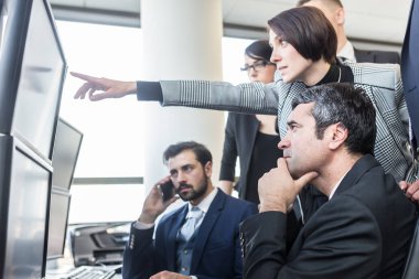 Şirket ofisindeki bilgisayar ekranlarında ticaret verilerine bakan başarılı iş ekibi.