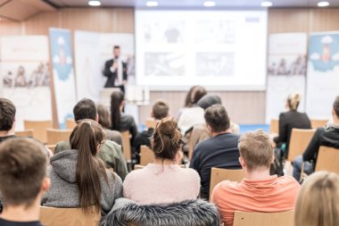 Üniversitedeki konferans salonunda sunum yapan adam.