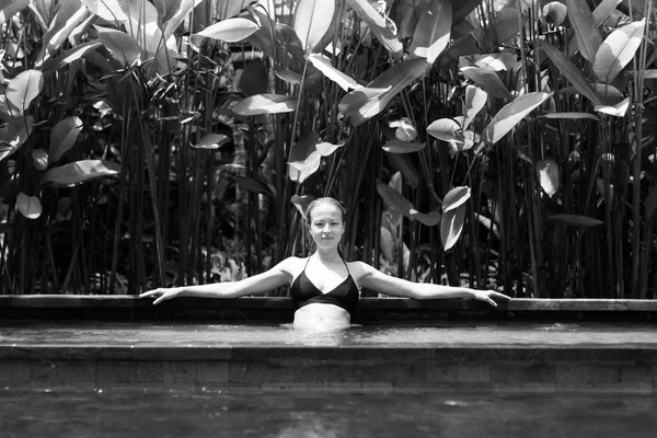 Sensual joven mujer relajante en el spa al aire libre piscina infinita rodeada de exuberante vegetación tropical de Ubud, Bali. Imagen en blanco y negro . —  Fotos de Stock