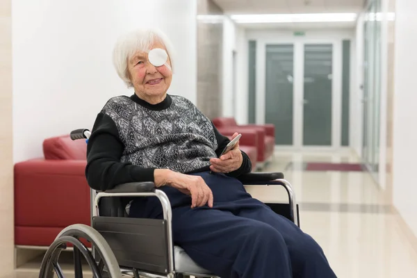 Einsame ältere 95-jährige Frau sitzt mit modernem Handy im Rollstuhl. — Stockfoto