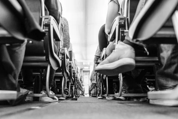 비행 하는 동안 그들의 좌석에 앉아 있는 통행인 상업 비행기 통로의 낮은 agle 보기. 흑백 사진. — 스톡 사진