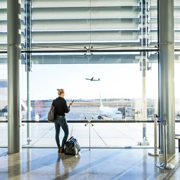 Giovane donna in attesa in aeroporto, guardando attraverso la finestra del cancello . — Foto Stock