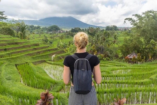 Fehér nő turista visel kis hátizsák nézi gyönyörű zöld rizs mezők és teraszok Jatiluwih Bali szigeten — Stock Fotó