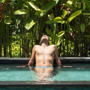 Ubud, Bali yemyeşil tropikal yeşillikile çevrili açık spa sonsuzyüzme havuzunda rahatlatıcı Adam.