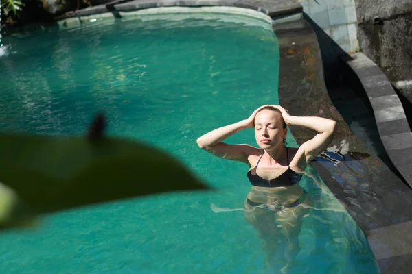 Smyslná mladá žena relaxující ve venkovních lázních nekonečný bazén obklopen svěží tropické zeleně Ubud, Bali. — Stock fotografie