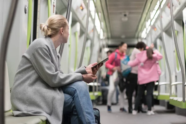 Güzel sarışın kadın metroyla seyahat ederken akıllı telefon kullanıyor.. — Stok fotoğraf